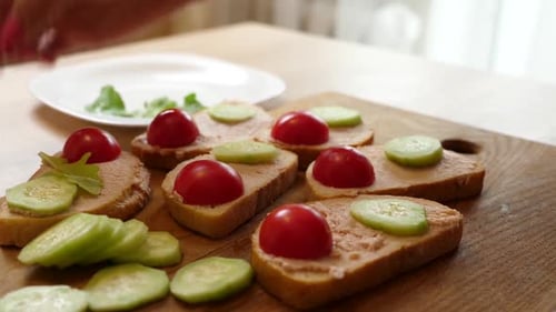 Person Preparing Open Sandwiches Topped with Vegetables