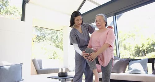 Therapist Helping Senior Woman Stretch Knee in Home