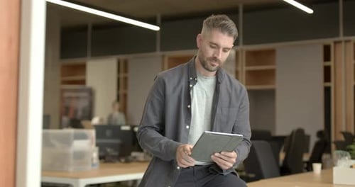 Portrait of Business man working in office on digital tablet sitting on desk