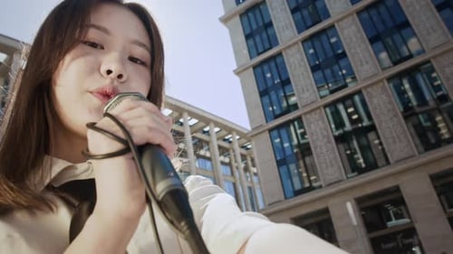 Young Woman Singing with Microphone in City