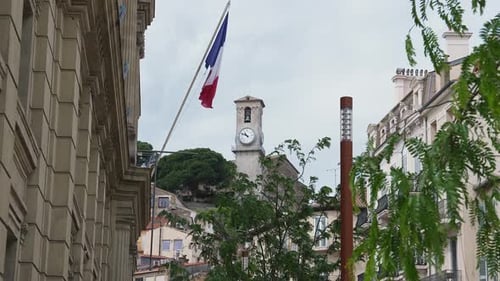 Historic Clock Tower and French Flag in Cannes France with City Life