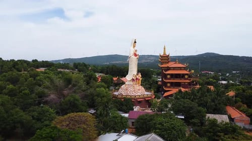 Aerial, buddhist temple with huge statue in the middle of rural palm tree jungle