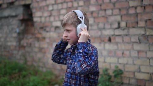 Young Boy Wearing Headphones and Dancing Energetically He's Dressed in a Blue Plaid Shirt and Black
