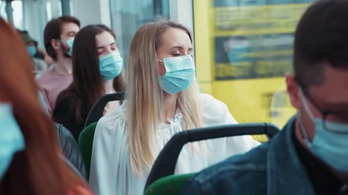 Masked passengers sitting inside a bus during the day