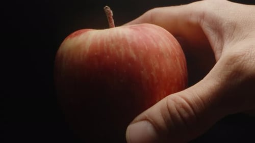 I put a red apple on the table . Black background, slow motion, close-up.