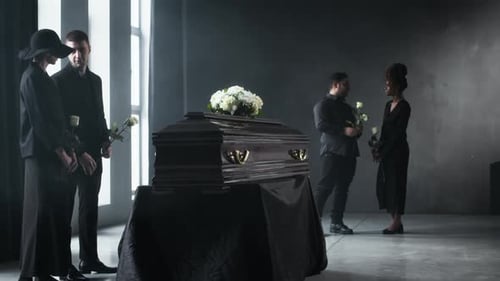 People Stand Around a Coffin Holding White Roses