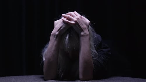 Woman With Head In Hands In The Dark