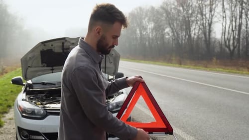 Young Man Preparing a Red Triangle to Warn Other Road Users Car Breakdown or Engine Failure Stop on