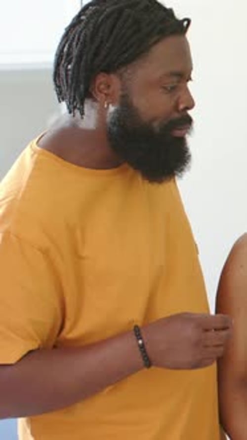 Vertical video: Tasting man in mustard tee sampling offered snack at kitchen door, with bracelet