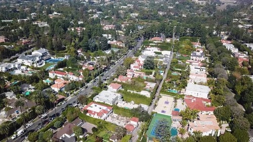 Villa and mansion in Beverly Hills with palm tree avenue in summer. Aerial top down shot. Traffic sc