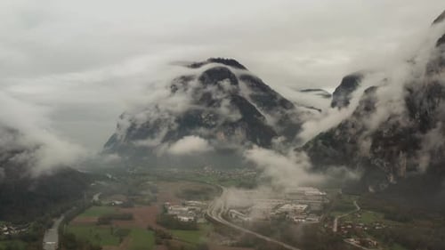 Aerial view of industrial zone in foggy Italian Alpine valley with highway