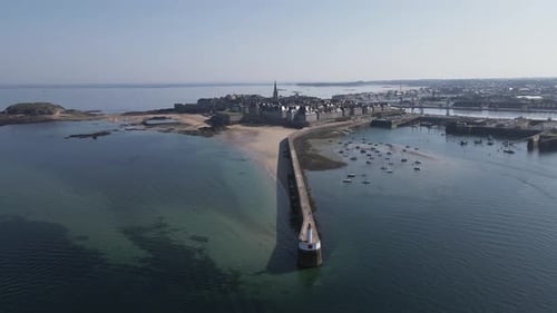 Môle des Noires lighthouse with Saint-Malo in background, Brittany in France. Aerial forward. Sky fo