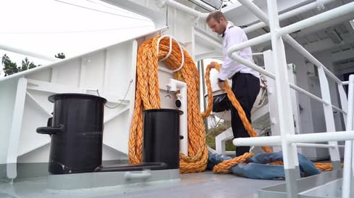 Passenger ship captain coils and stores mooring rope before sailing