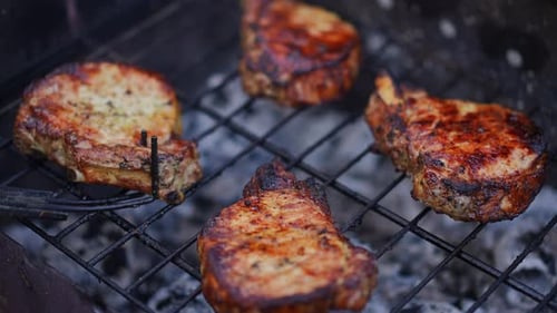 Closeup Turning Delicious Steaks on Grill Outdoors in Slow Motion
