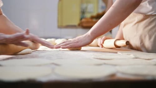 Cooks Roll the Dough for Baking Pieces of Raw Dough