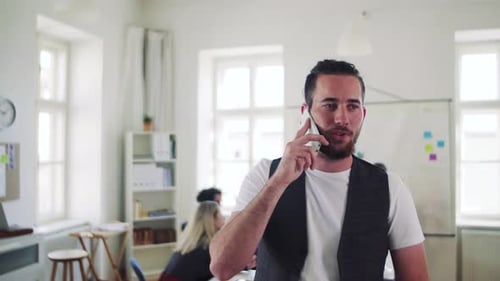 Young hipster businessman with smartphone working in modern office space