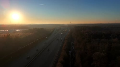 Sunrise during cold winter day on american highway. Aerial top down flyover. Leafless colored trees
