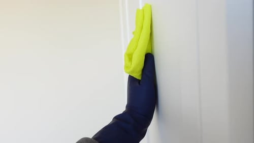 Gloved Hand Wiping Surface with Yellow Cloth