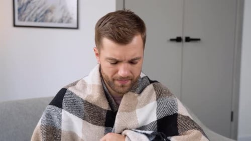 Un joven tiene un termómetro para controlar la fiebre y medir la temperatura corporal