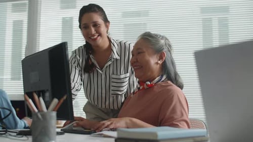 Woman Helping Senior Woman at Computer in Office