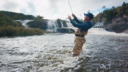 Man Fly Fishing in River by Scenic Waterfall