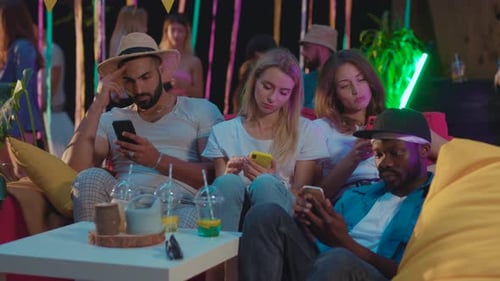 Young Adults on Phones at Party in Evening