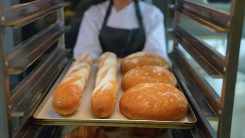 Baker Takes Fresh Baked Bread From Cooling Rack