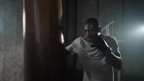 Boxer Training Hitting Punching Bag African American Sweated Sportsman Practicing Punches in Gym