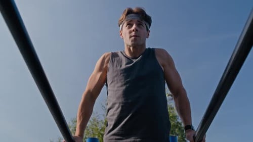 Fit Man Doing Dips in Outdoor Gym on Sunny Day