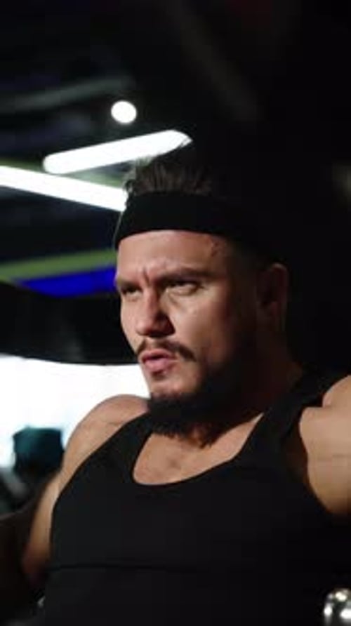 Closeup of Focused Bearded Athlete Gripping a Bar During an Intense Strength Workout on a Machine in