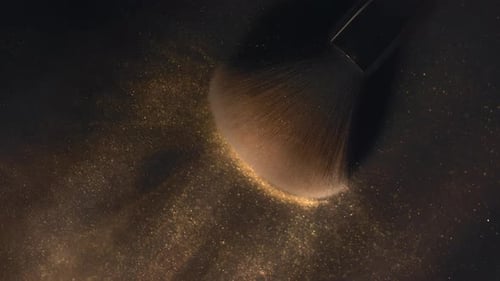 Makro-Aufnahme von Make-up-Pinsel und goldenem Gesichtspuder, die in Superzeitlupe entstehen, elegantes Luxus-Make-up