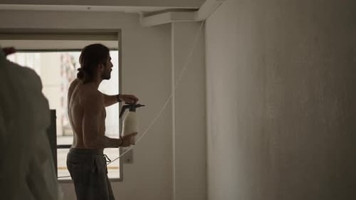 Man Spraying White Wall Indoors