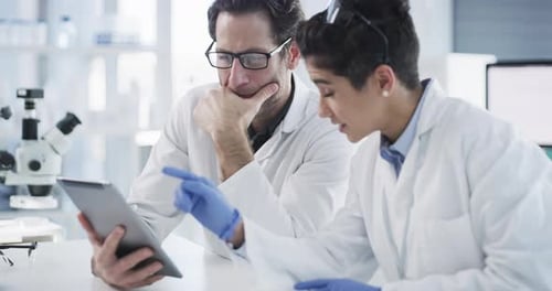 Scientists Discussing Research Data on a Tablet