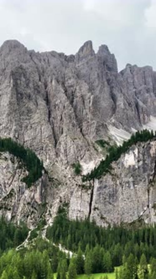 Aerial drone view of steep limestone cliffs and alpine forest in the Dolomites. The rugged mountain