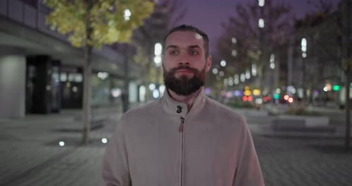 A Young Man with a Stylish Trendy Hairstyle and Beard in Casual Clothes Walks Down the Street