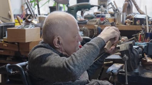 Senior Elderly Master Jeweler in Wheelchair Works in a Workshop