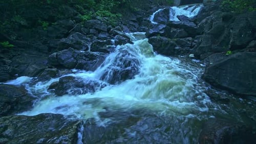 Low Angle Closeup of Waterfall Flowing Stream in a Dark Moody Forest