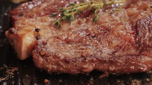 Fresh Marbled Beef with Pepper Salt and Rosemary Closeup Macro Cooking Juicy Steak on Grill with Oil