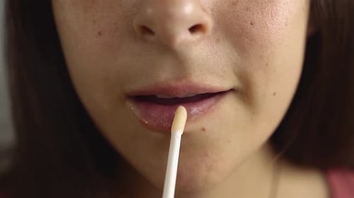 Woman Applies Shiny Lip Gloss Close Up
