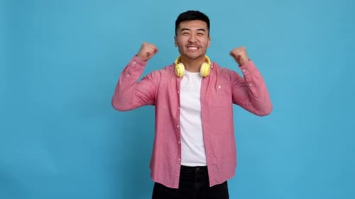 Excited Young Adult Expressing Joy on Blue Background