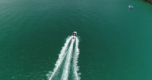 Aerial drone shot catching up with speedboat and following from behind in a turquoise calm sea