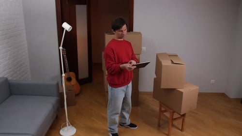 Young Adult with Boxes and Tablet in Home