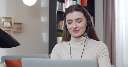 Caucasian Young Woman in Headset Working at Computer and Talking Videochatting Call Center Worker at