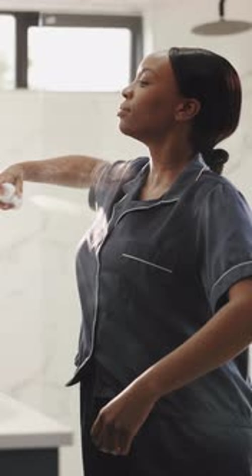 Woman Sprays Facial Mist in Bright Modern Bathroom