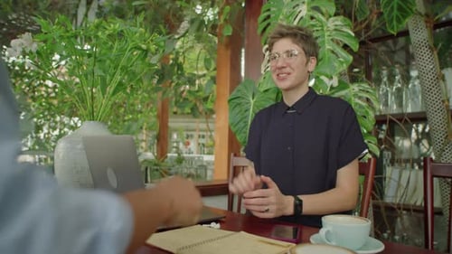 Businesswoman Greeting Colleague with Handshake in Outdoor Cafe