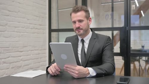 Professional Man Video Calling on Tablet in Office