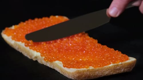 Red Caviar Being Spread on Bread Slice