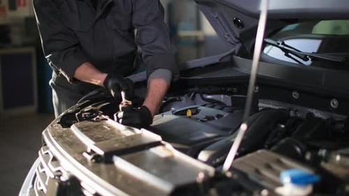Man Working on Car Engine in Repair Shop