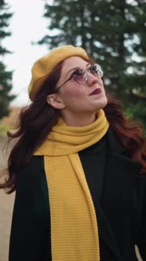 RedHaired Artist Adjusts Hair in Autumn Garden with Yellow Beret