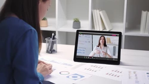 Woman Attends Virtual Meeting, Reviews Charts and Graphs